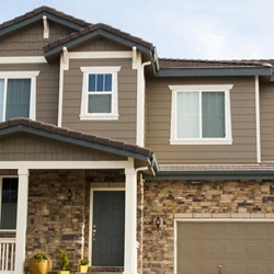 A two-story house with stone veneer, a garage door, and a dark front entry.