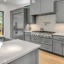Modern kitchen with grey cabinets, stainless steel appliances, and a tiled backsplash.