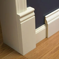 White doorframe with matching skirting board on a wooden floor against a dark blue wall.